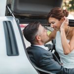 A wedding portrait featuring a bride and groom in the trunk of a car.