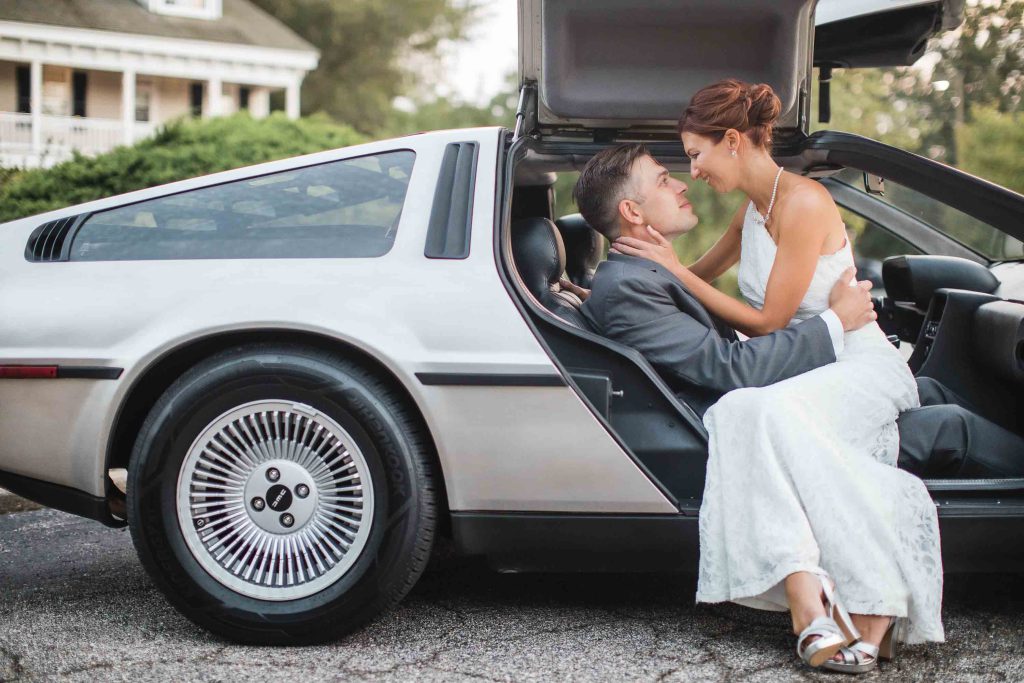 A wedding portrait of a bride and groom kissing in the back of a Delorean.