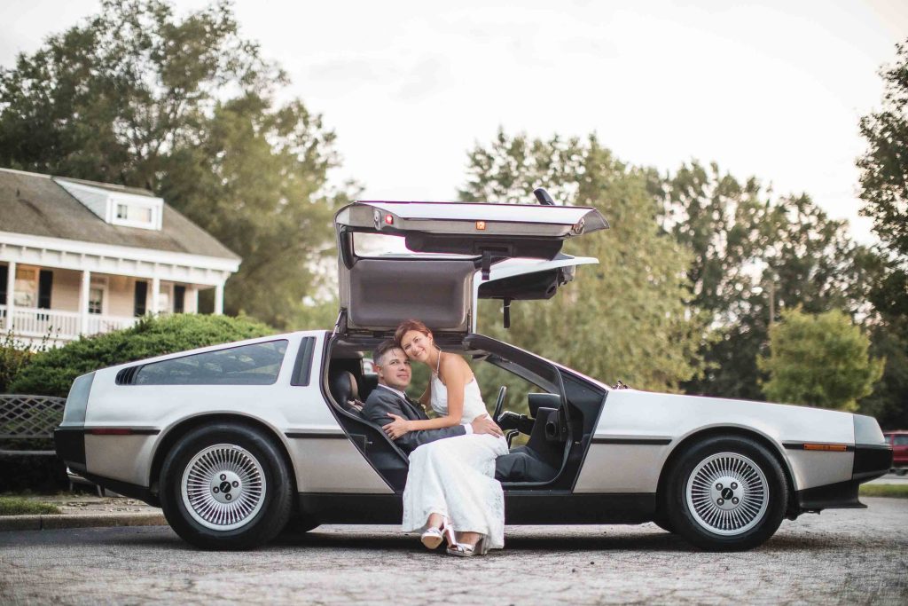 A wedding portrait of a bride and groom with a delorean car.