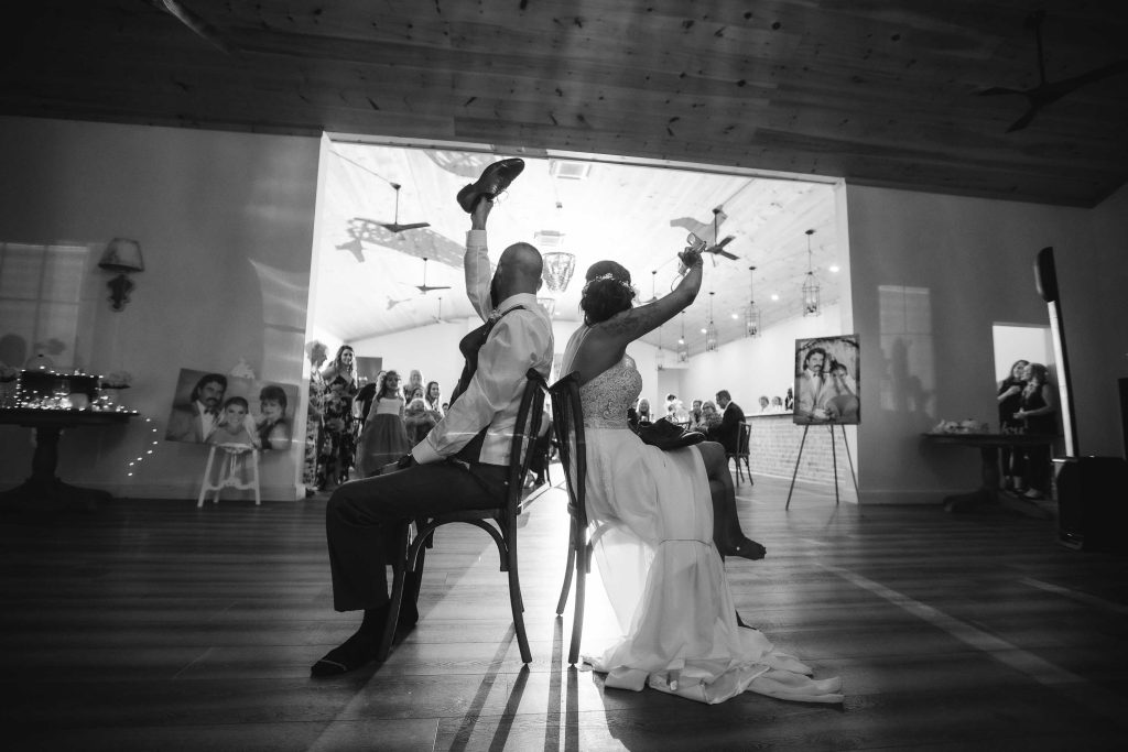 A bride and groom sitting on chairs at their wedding reception.