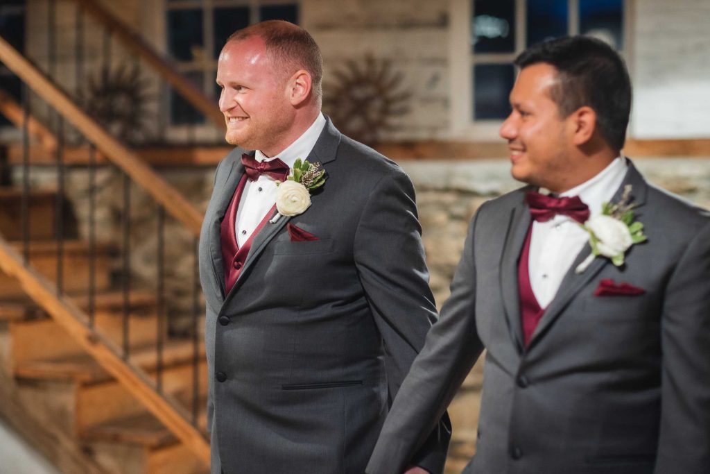 Groomsmen in tuxedos descending the stairs at a wedding reception.