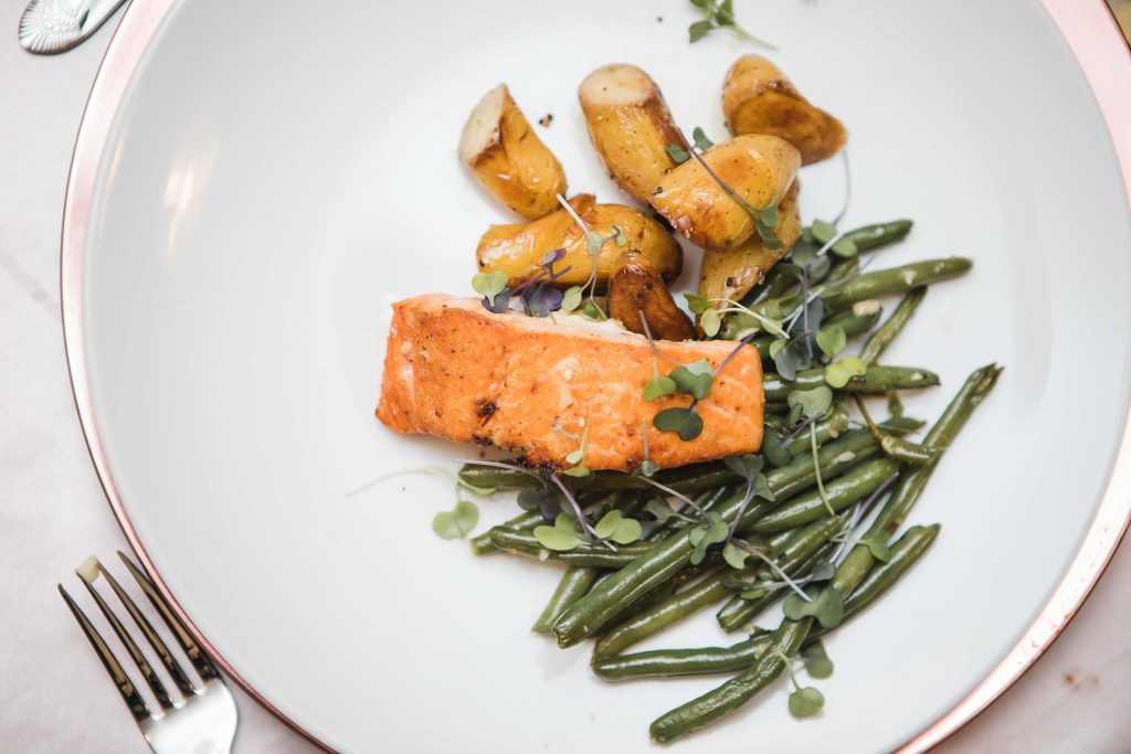 A wedding plate with salmon, green beans and potatoes.