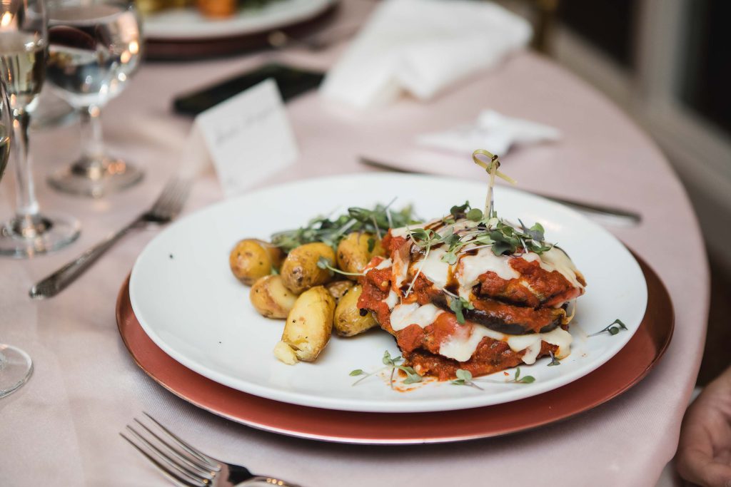 A wedding table setting with detailed food and a glass of wine.