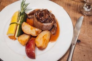 A plate with wedding details, including meat, potatoes and vegetables on it.