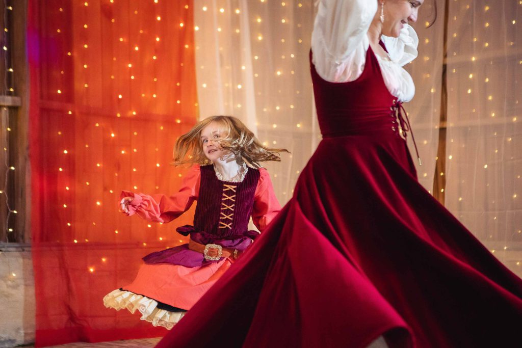A woman and a little girl dancing at a wedding reception in a red dress.