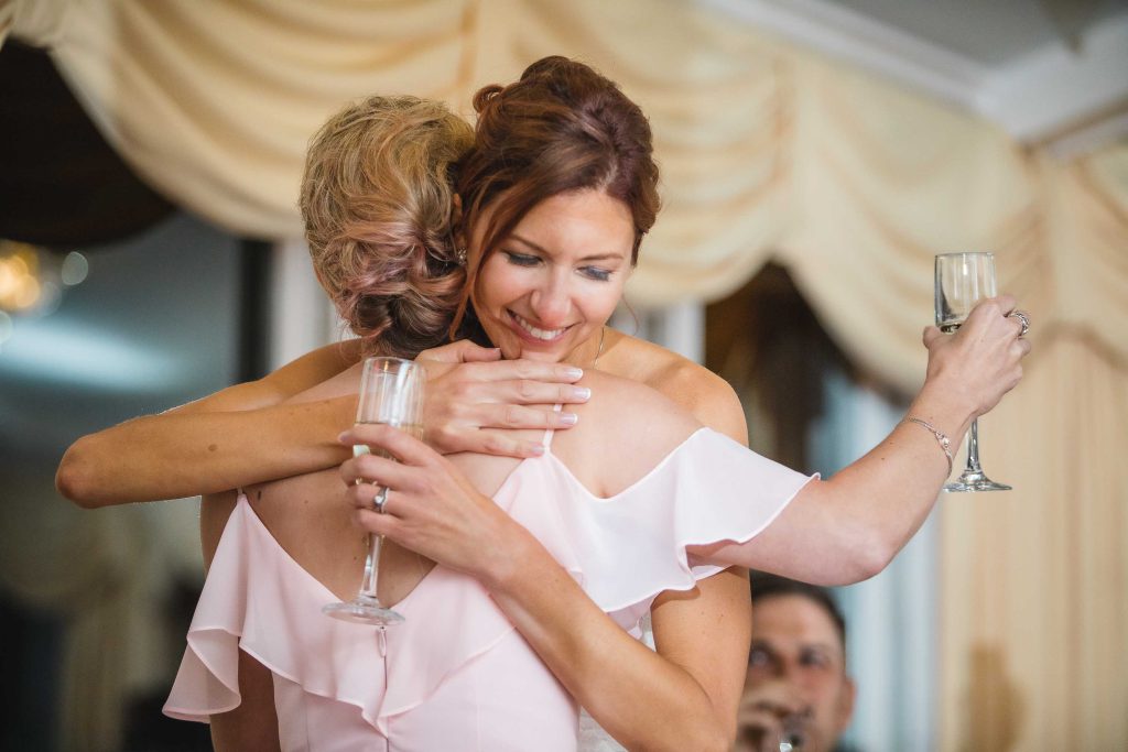 Two women embracing at a wedding reception.