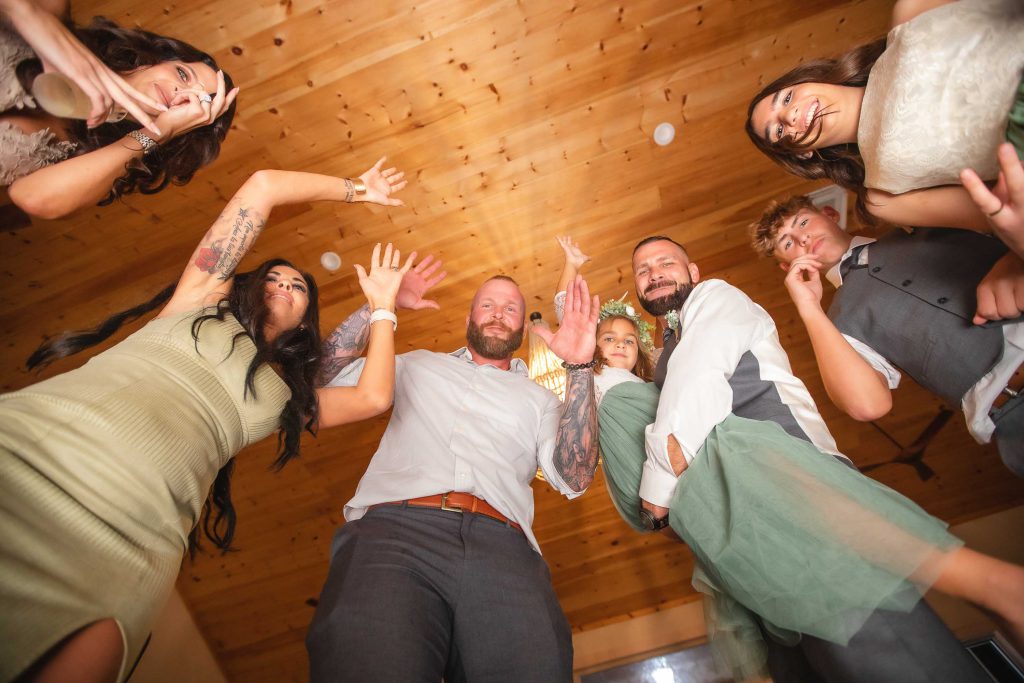 A group of people with their hands up in the air at a wedding reception.