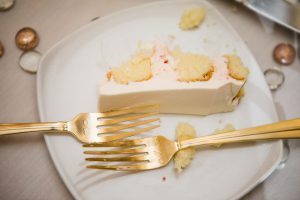 A piece of cake with gold forks in wedding details.