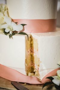 A detailed wedding cake with a slice taken out of it.