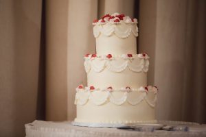 A detailed white wedding cake is sitting on a table.