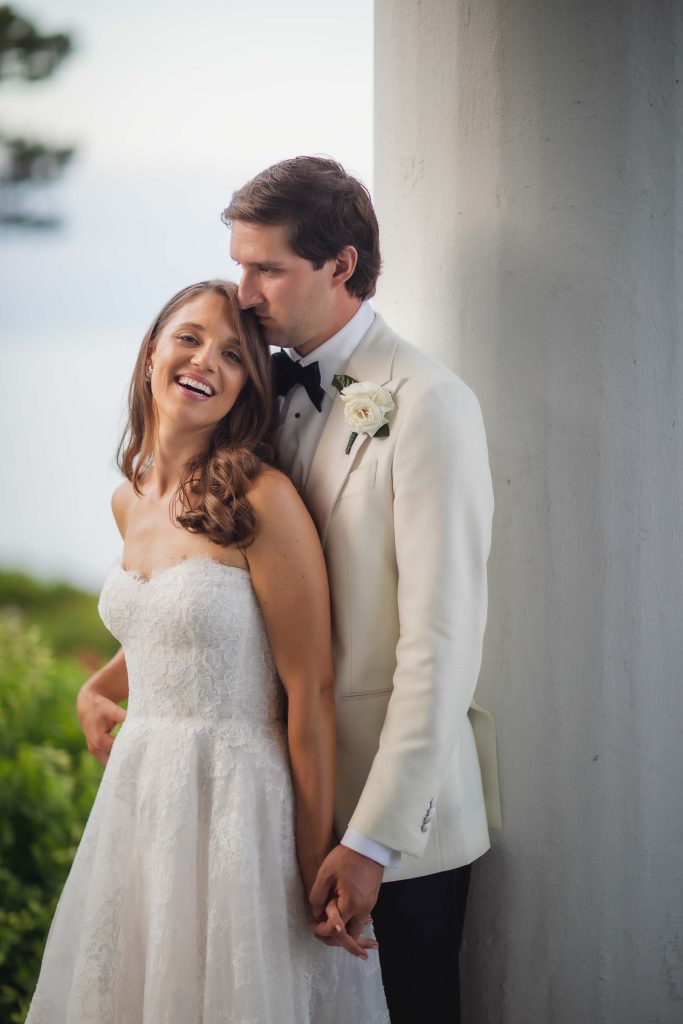 A bride and groom in a tuxedo pose for a wedding photo.