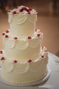 A detailed wedding cake adorned with red roses.