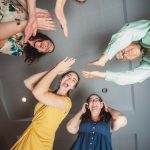 A group of women raising their hands in celebration at a wedding reception.