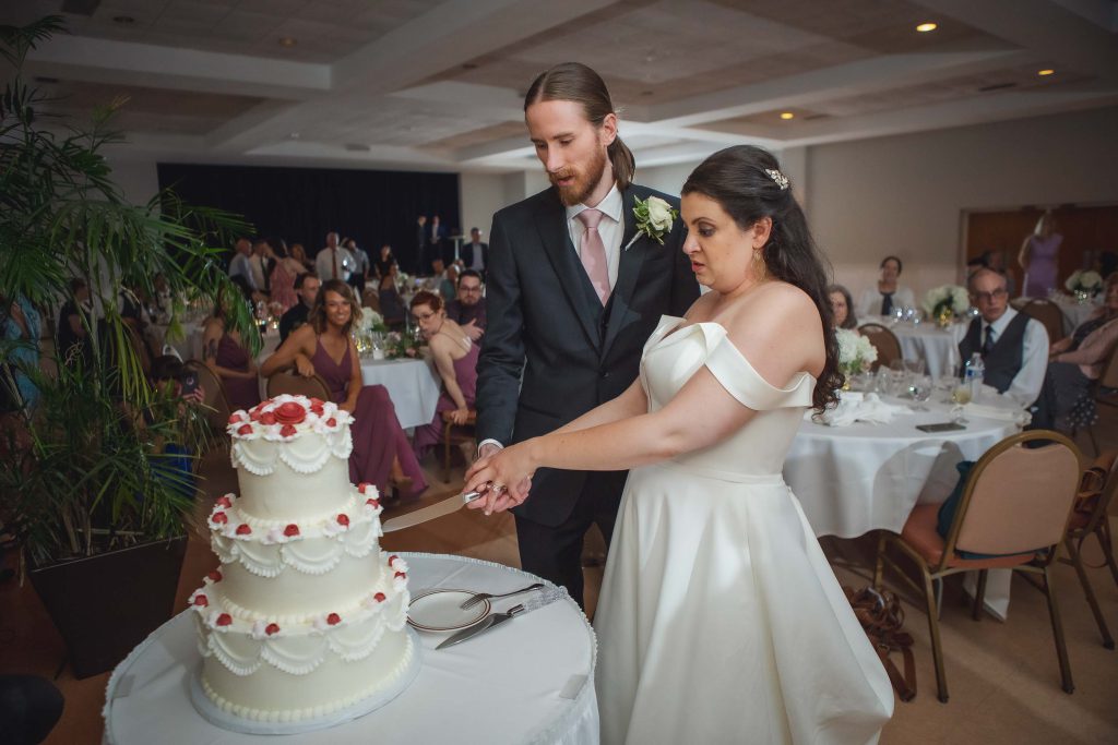 A bride and groom enjoying a wedding reception cake-cutting tradition.