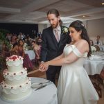 A bride and groom enjoying a wedding reception cakecutting tradition.