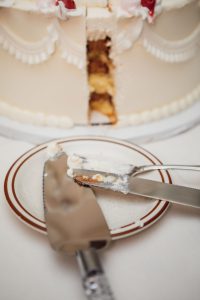 A detailed white wedding cake with a slice taken out of it.