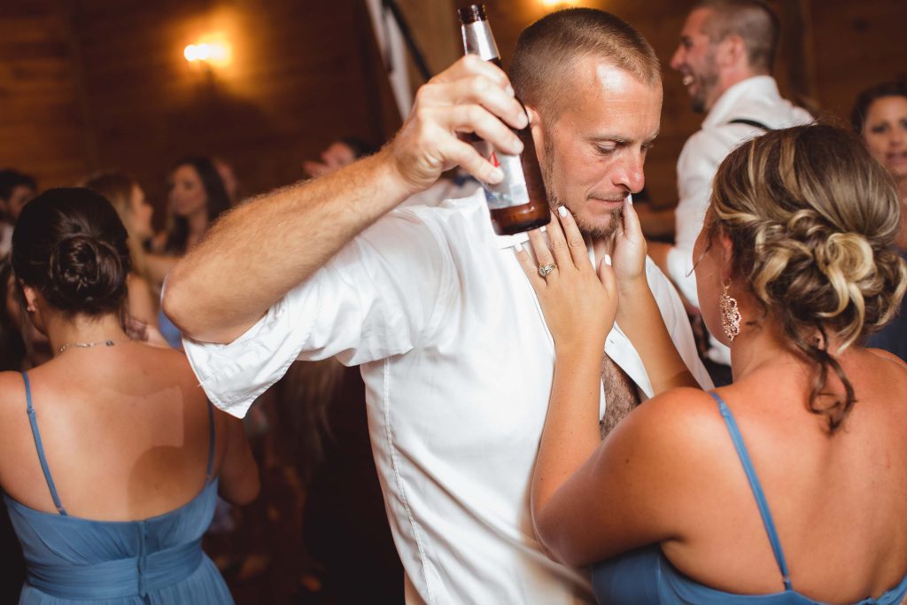 A man is holding a beer at a wedding reception.