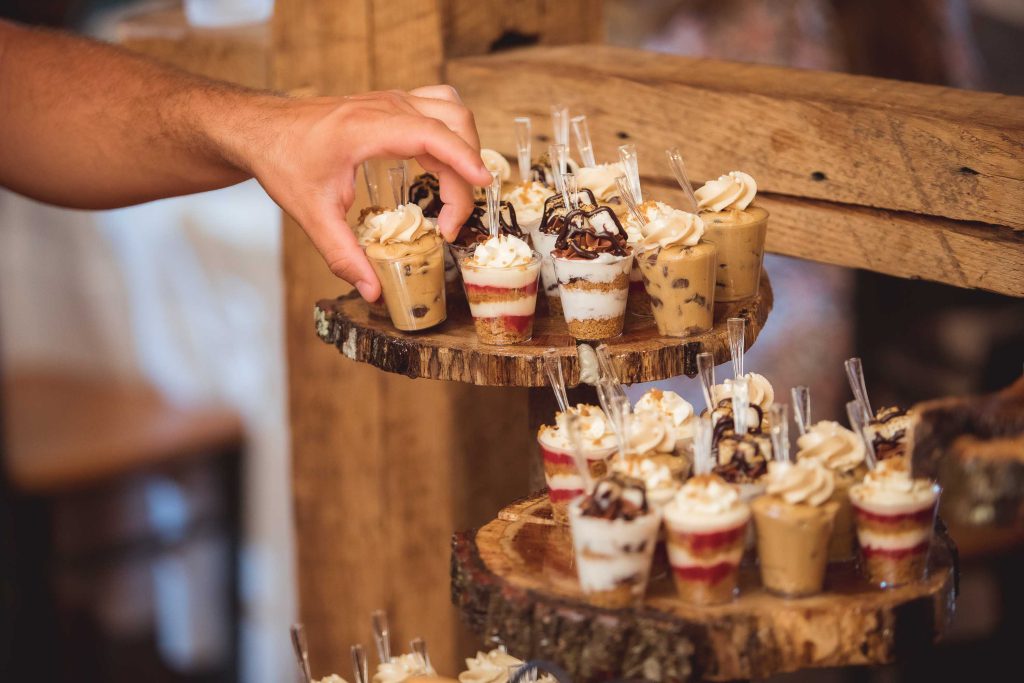 A person is putting wedding cupcakes on a wooden stand, paying attention to details.