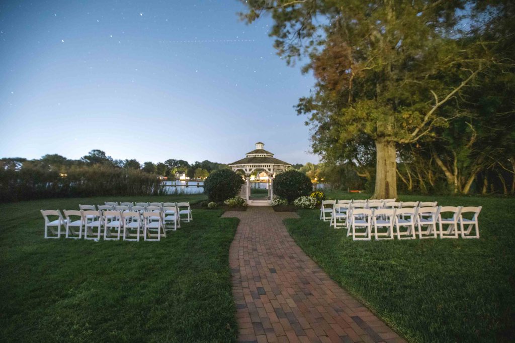 A wedding ceremony set up at night with intricate details and a gazebo.