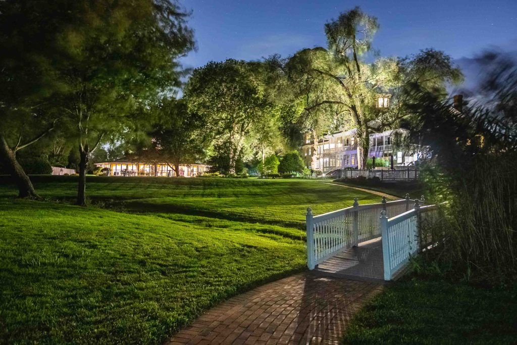 A pathway leading to a house in a grassy area at night, adorned with intricate details.