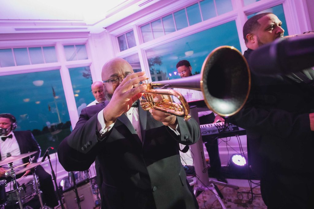 A man in a tuxedo playing a trumpet at a wedding reception.