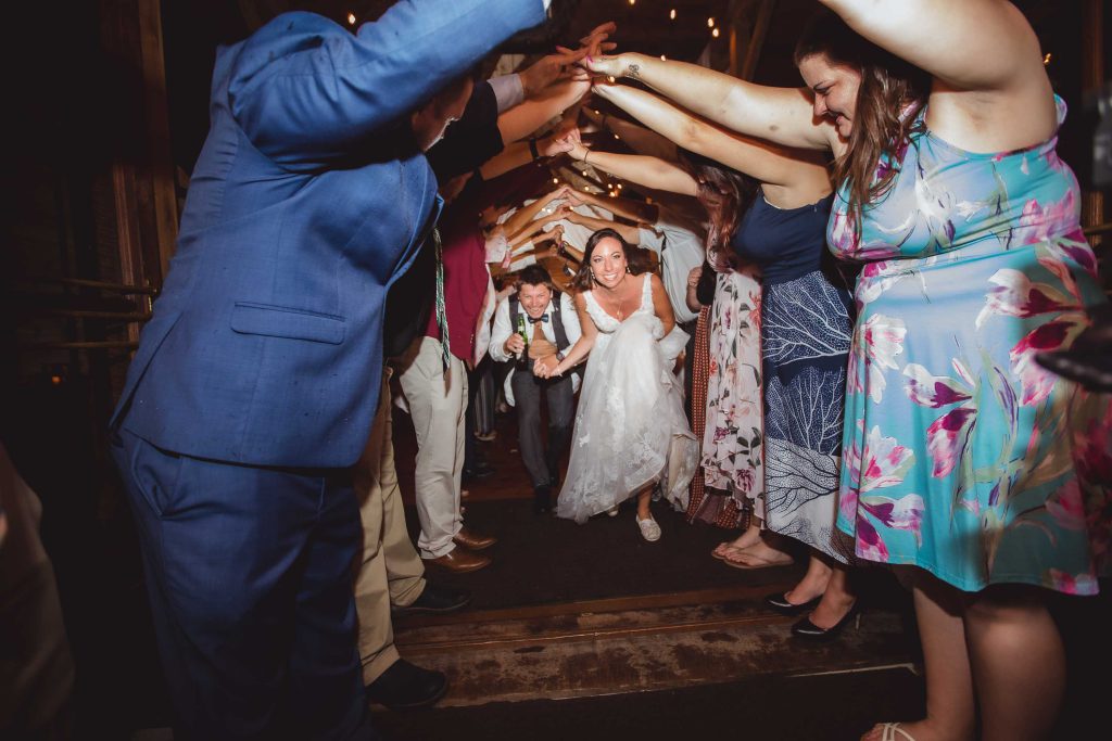 A bride and groom are throwing their hands up in the air during their wedding reception.