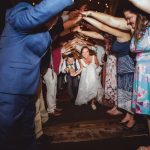 A bride and groom are throwing their hands up in the air during their wedding reception.