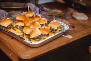 A tray of sliders at a wedding reception on a wooden table.