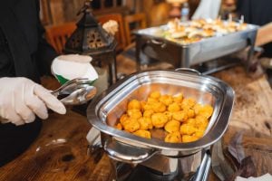 A waiter is preparing food with attention to details for a wedding buffet.