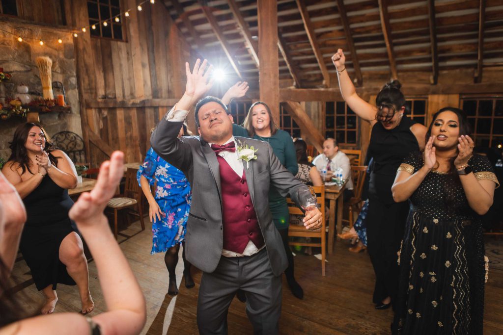 A man in a suit dancing at a wedding reception.