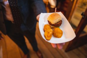 A man in a suit is holding a plate of food at a wedding.