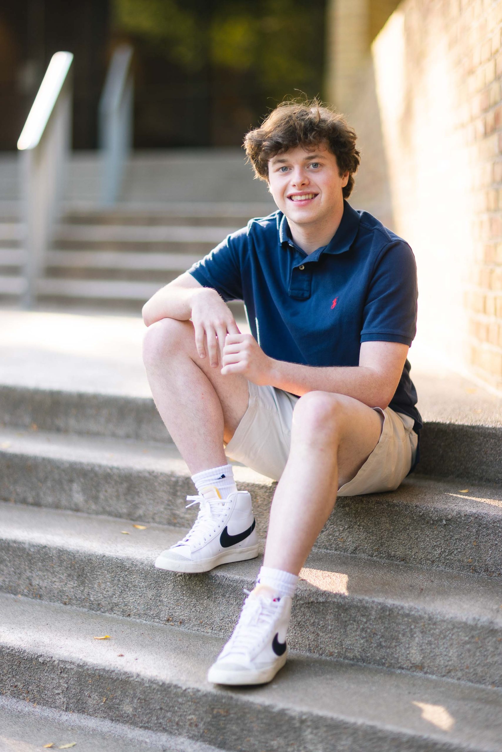 A senior high school student sitting on steps in a blue shirt.
