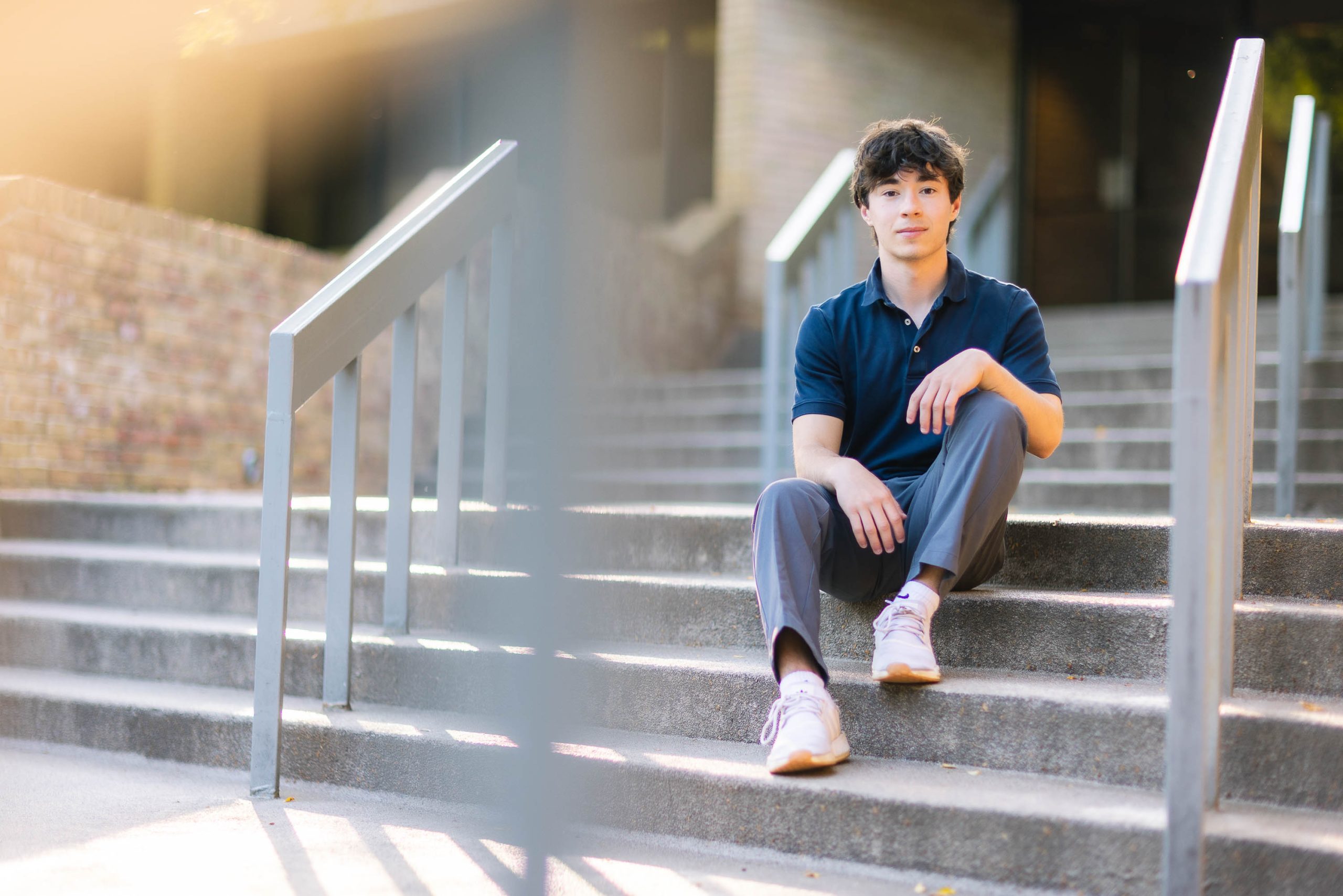 A senior graduate posing for a portrait on the steps of a building.