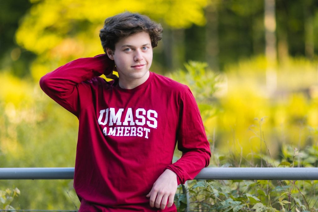 A young man leaning against a railing during his high school graduation.