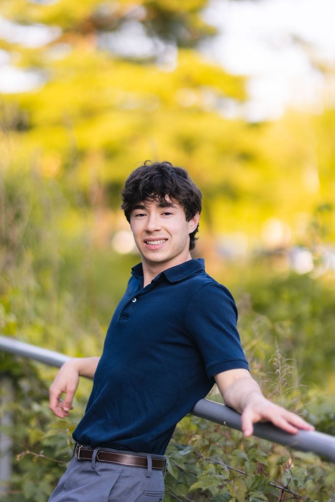 A high school senior leaning against a railing.