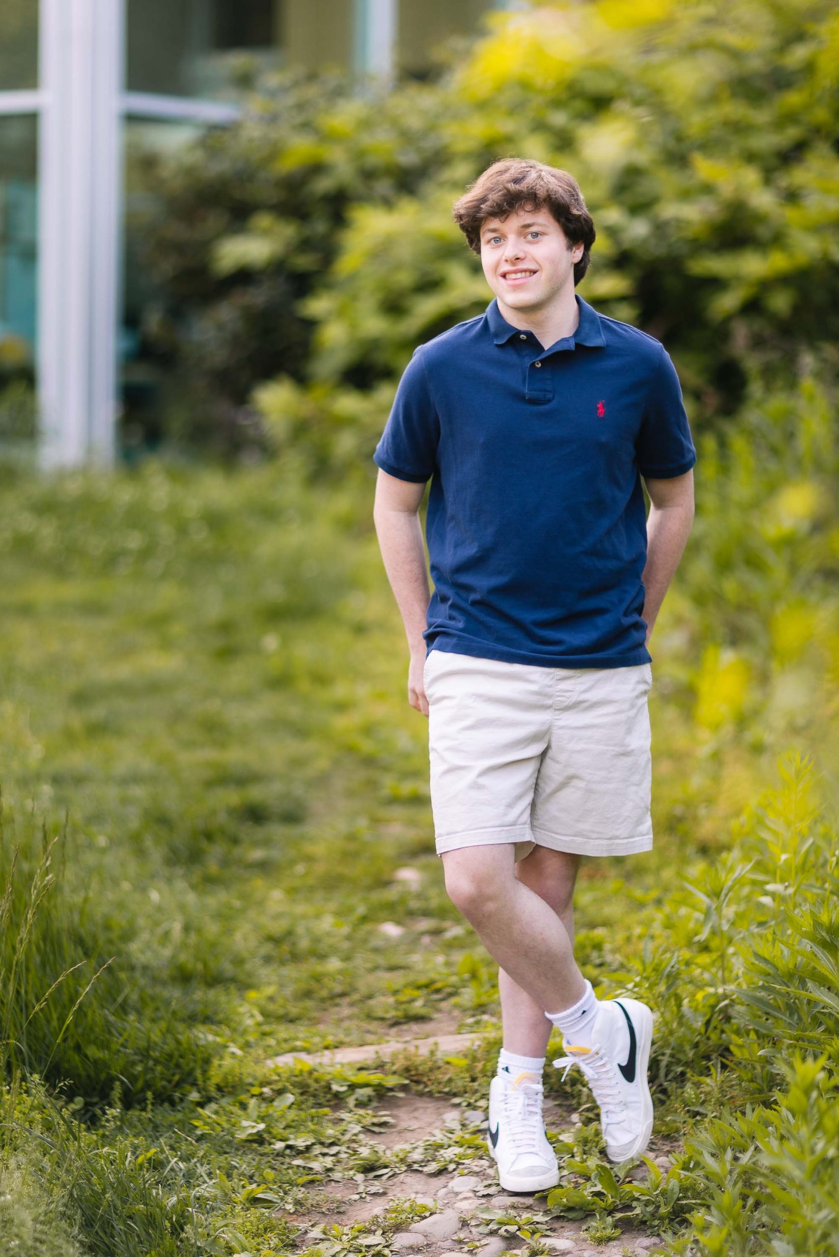 A senior man in a blue shirt and shorts standing in a grassy area.