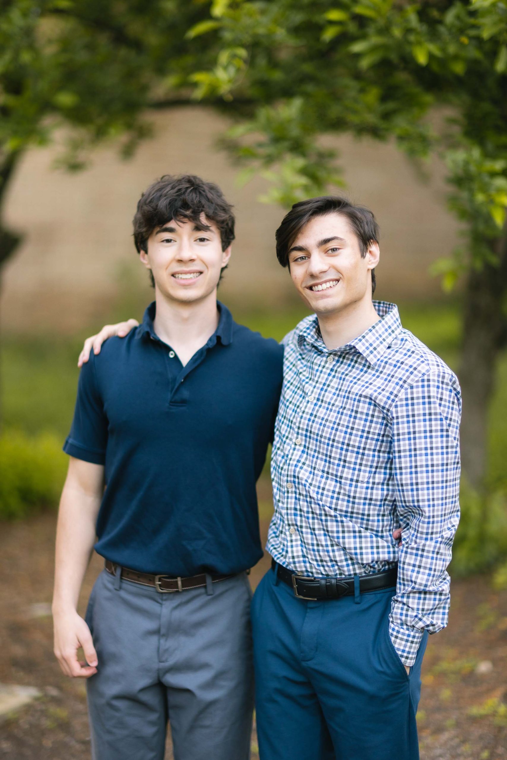 Two young high school seniors posing for a portrait in a park.