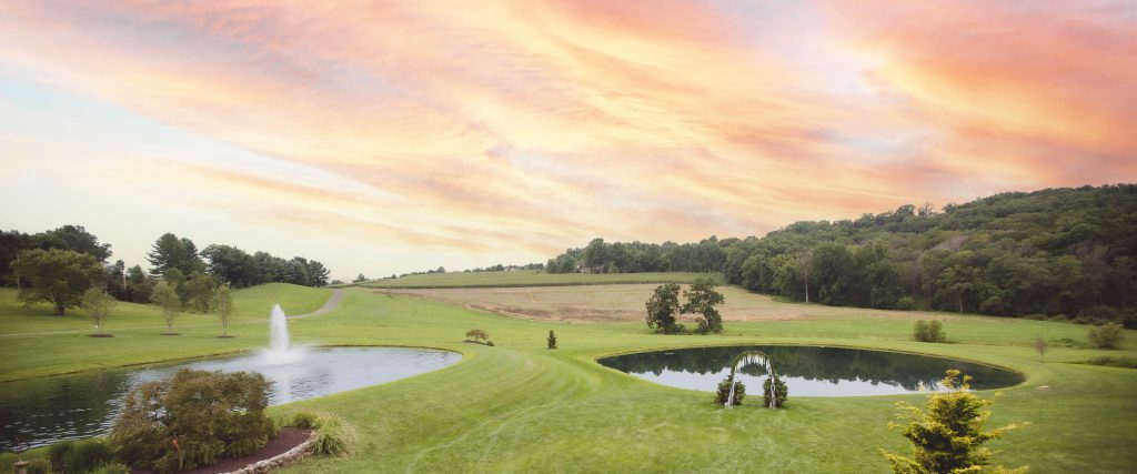 A green field in Stone Ridge Hollow, Bel Air, Maryland with a pond featuring a fountain.