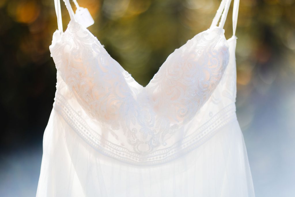 A detailed wedding dress hanging on a hanger.