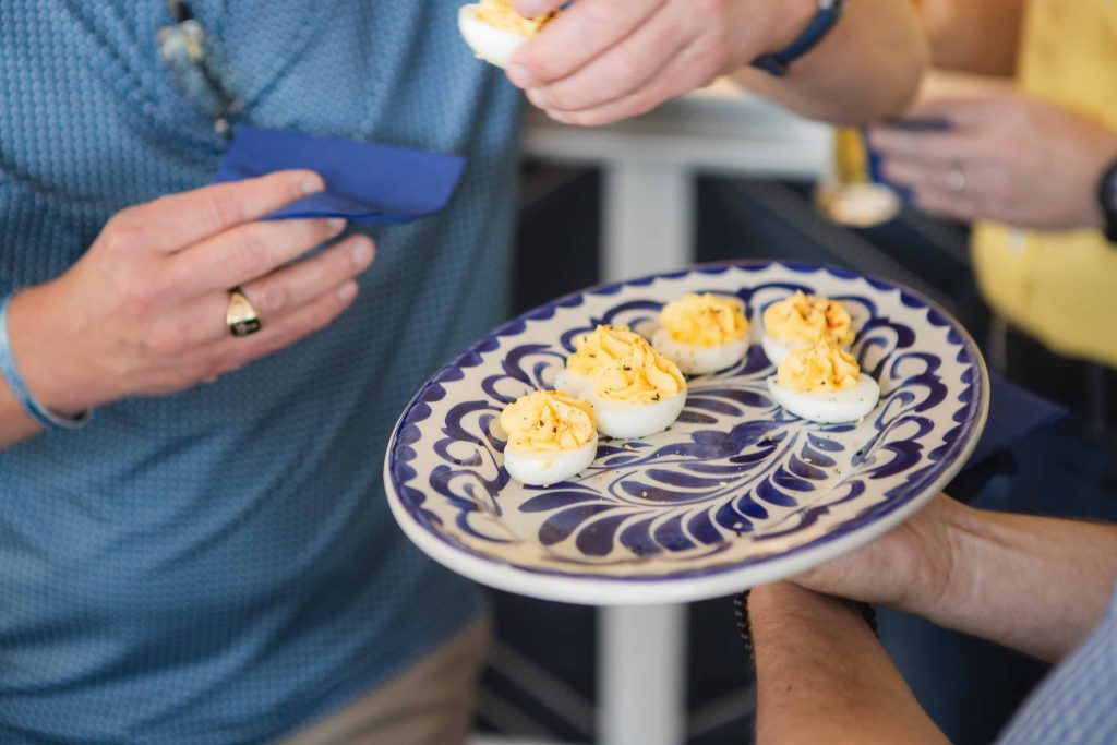 A group of people holding a plate of deviled eggs at a birthday party.
