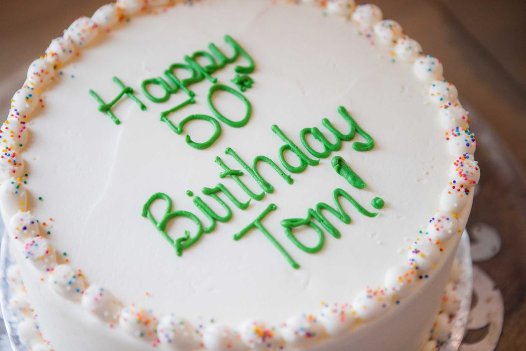 A festive 50th birthday cake on a plate at a birthday party.