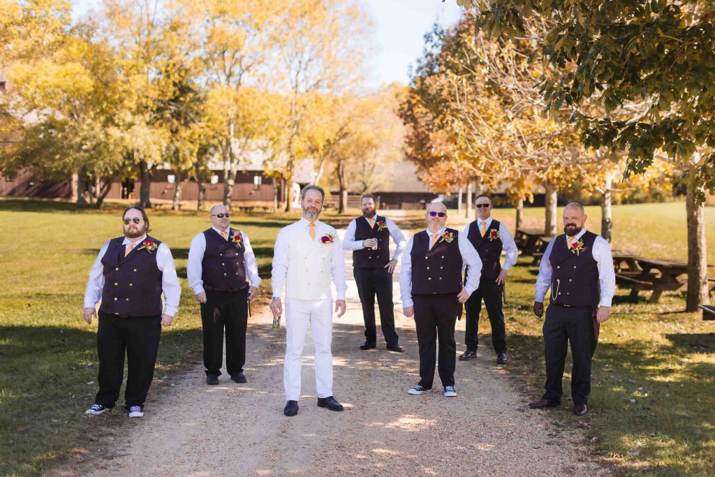 A group of groomsmen posing for a wedding portrait on a dirt path.