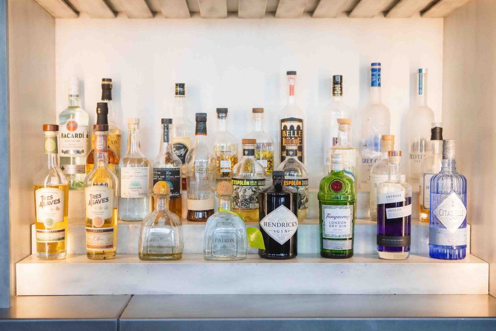 Many bottles of liquor are lined up on a shelf for a birthday party.