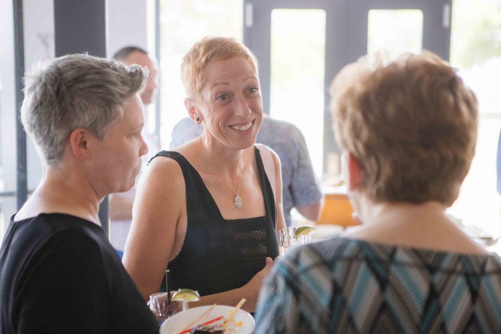 A group of people at a birthday party talking to each other.