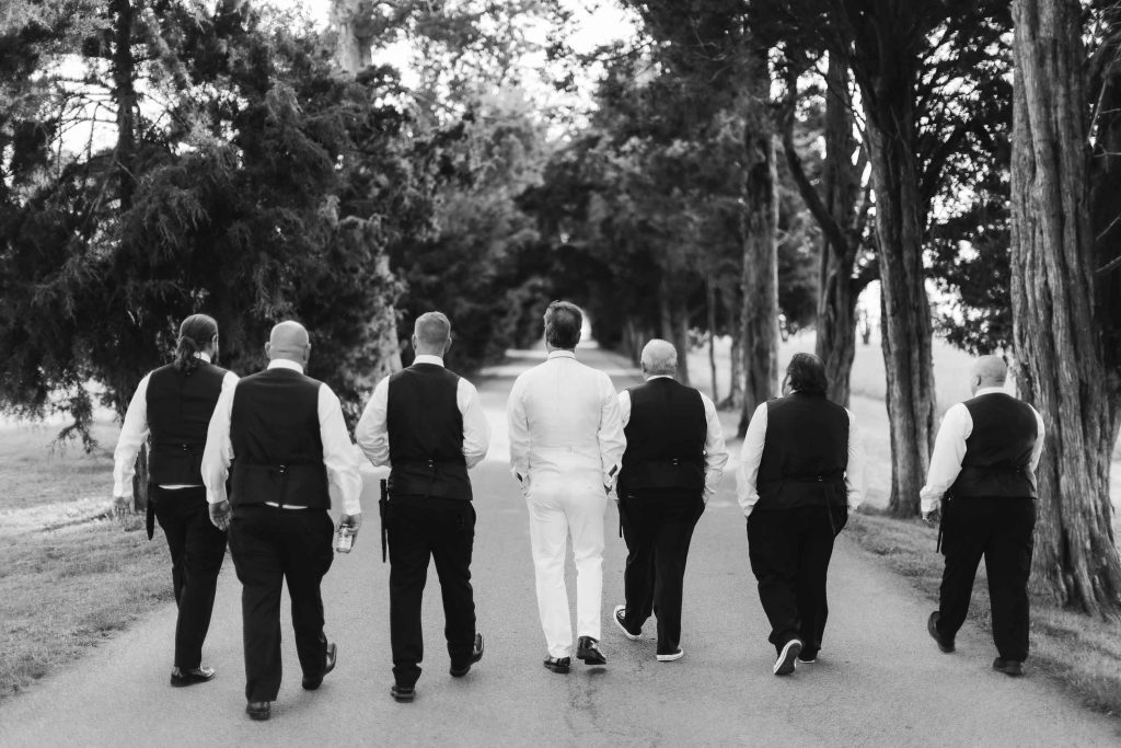 A wedding party walking down a road.