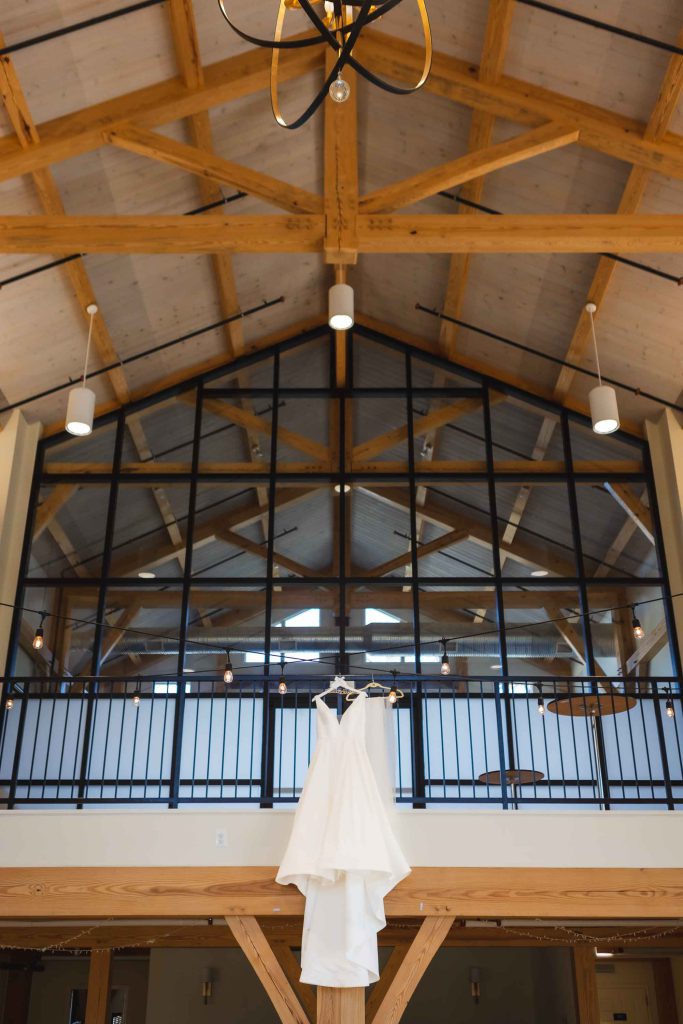 A wedding dress hangs elegantly from the ceiling, adorned with intricate details.