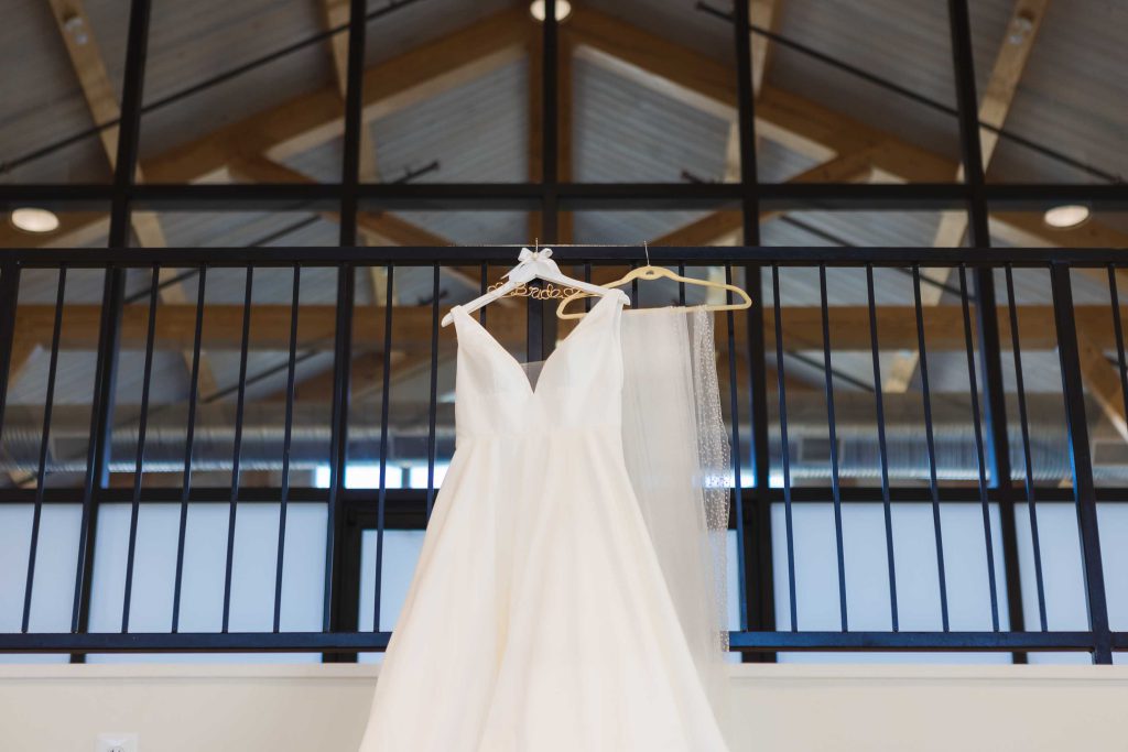 A wedding dress hanging in a barn, showcasing intricate details.