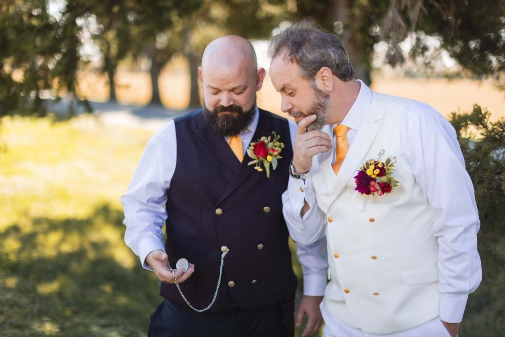 Two men in wedding attire standing next to each other.
