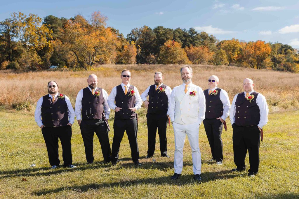 A wedding portrait of groomsmen standing in a field.
