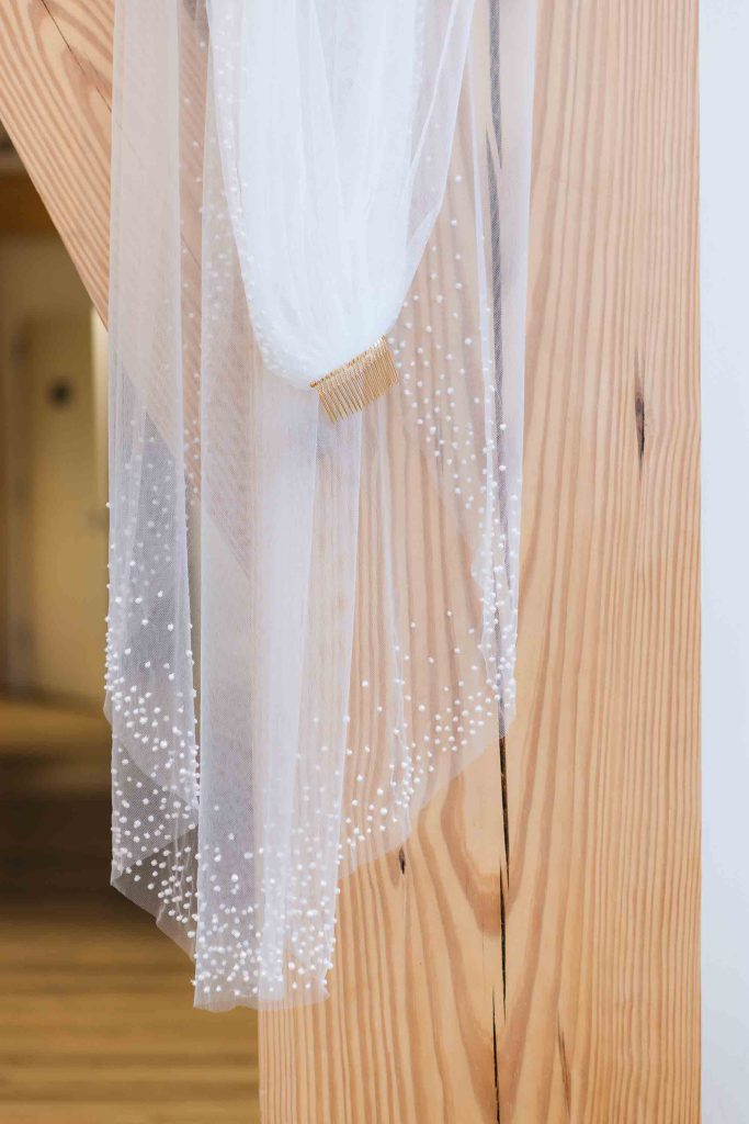 A wedding veil hanging from a wooden door.